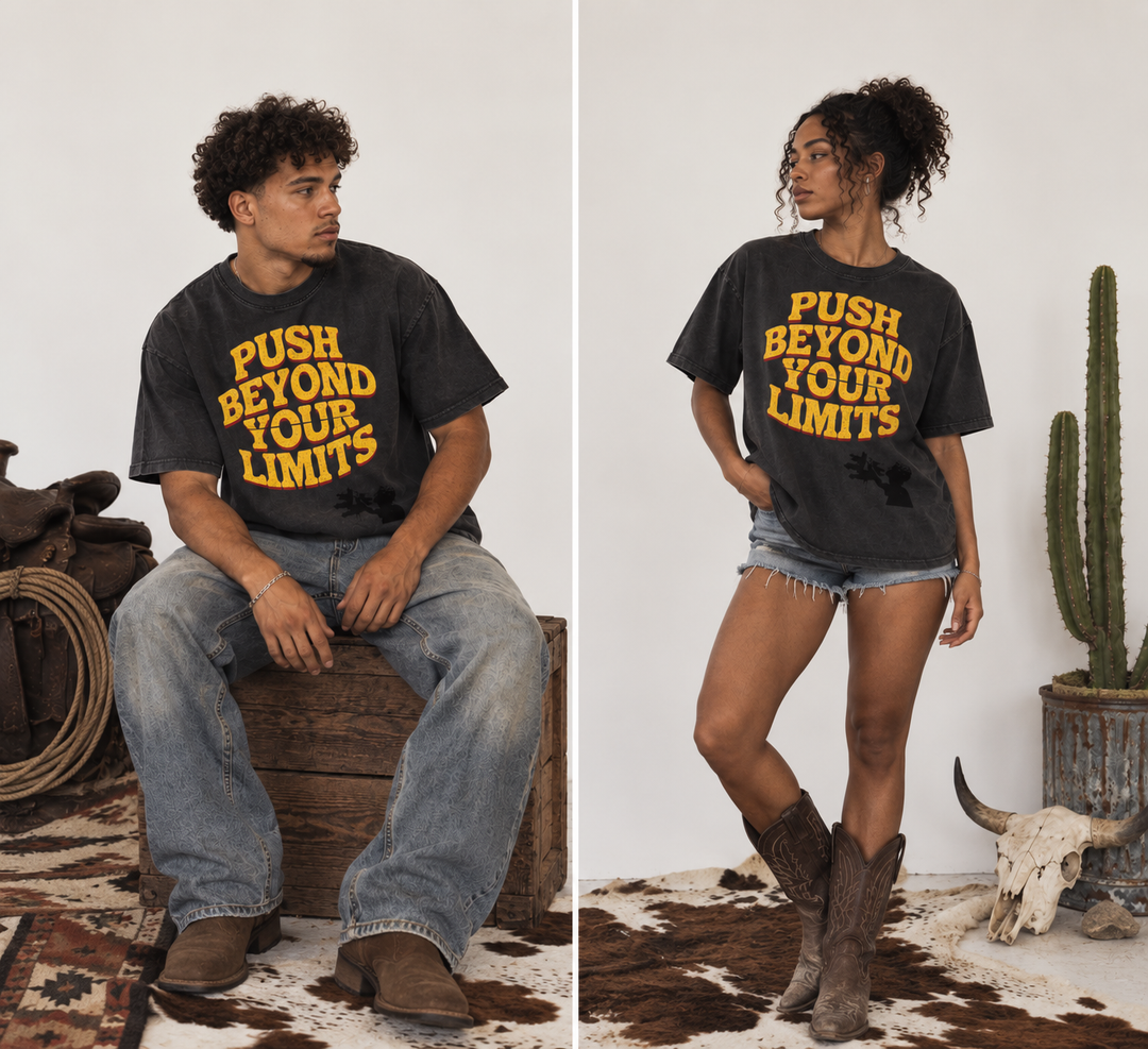 A split-screen lifestyle image showing a man and a woman wearing a dark charcoal gray graphic t-shirt with yellow text that reads 'PUSH BEYOND YOUR LIMITS'. The man is sitting on a wooden crate wearing blue jeans, and the woman is standing in a western outfit with denim shorts and brown boots.