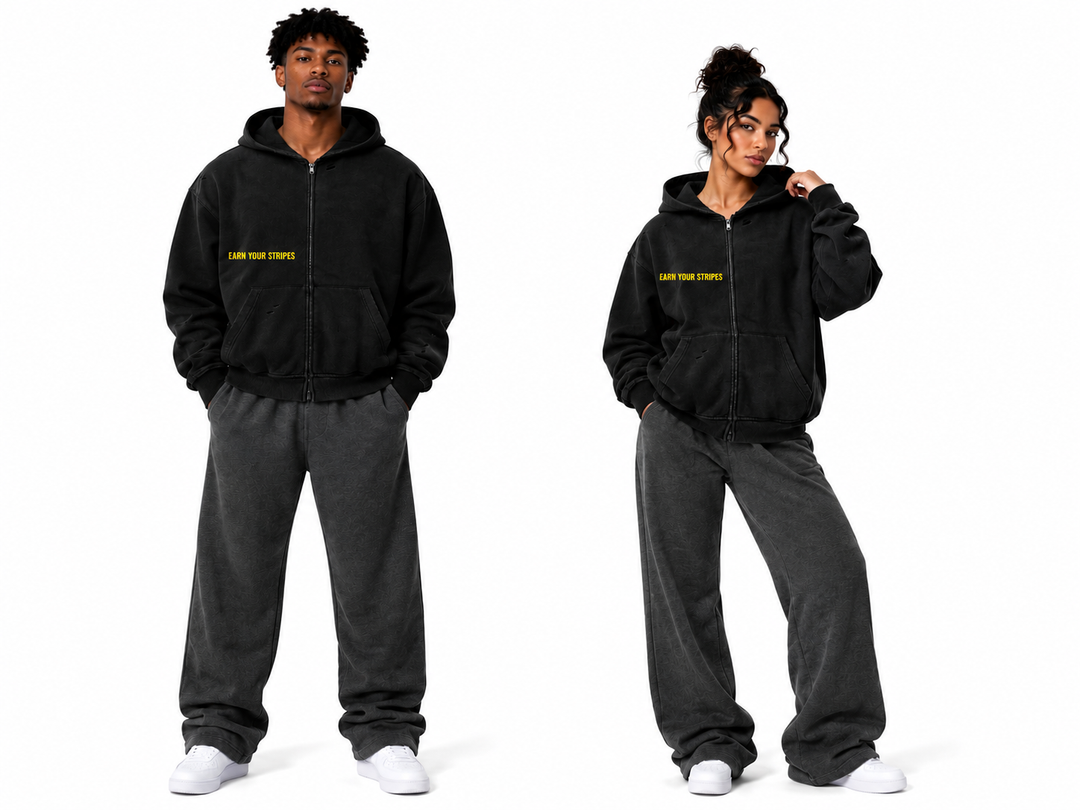 Two models wearing matching black zip-up hoodies with yellow 'SAVE YOUR STAFFS' text on the chest, paired with dark gray sweatpants and white sneakers, shown against a plain white background.