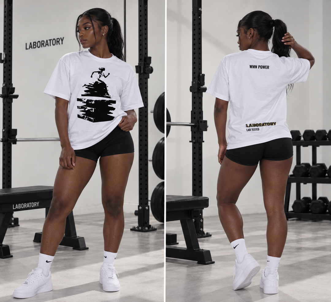 A woman modeling a white graphic T-shirt and black athletic shorts in a gym setting, shown in a side-by-side front and back view. The shirt features a black abstract graphic on the front and 'WE ARE LABORATORY' printed on the back.
