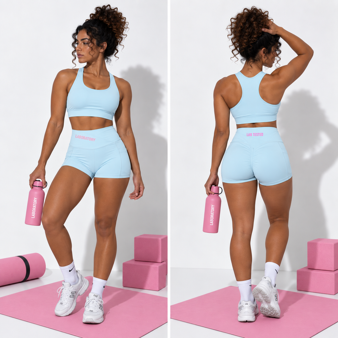A woman modeling a light blue athletic set consisting of a sports bra and high-waisted shorts, shown in a side-by-side front and back view. She is standing on a pink yoga mat with pink blocks and a pink water bottle.