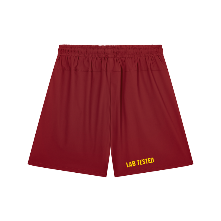 Red athletic shorts with an elastic waistband and yellow 'LAB TESTED' text printed on the lower left leg, shown against a plain white background.
