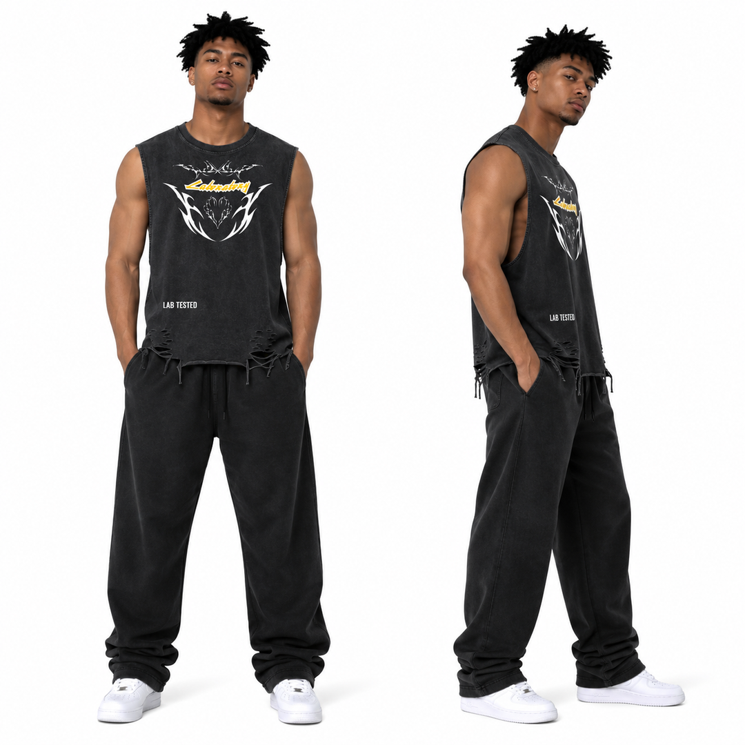 A model is shown from the front and back wearing a black washed sleeveless tank top with a white and yellow graphic on the chest, paired with matching black sweatpants and white sneakers, against a plain white background.