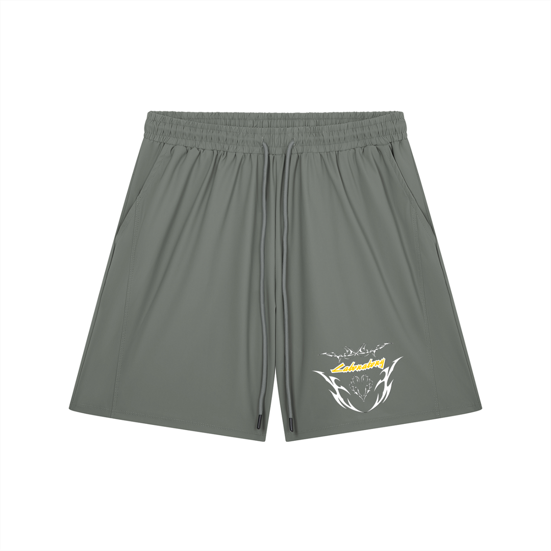 A pair of olive green athletic shorts with an elastic waistband and drawstring, featuring a white and yellow graphic logo on the lower left leg, displayed against a solid white background.