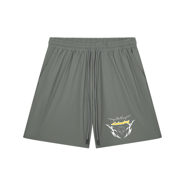 A pair of olive green athletic shorts with an elastic waistband and drawstring, featuring a white and yellow graphic logo on the lower left leg, displayed against a solid white background.