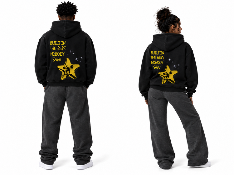 Two views of a person modeling a black hoodie from the back, wearing dark gray sweatpants and white sneakers. The hoodie features a yellow star graphic and the text 'BUILT IN THE RAIN NOBODY SAW' printed on the back.