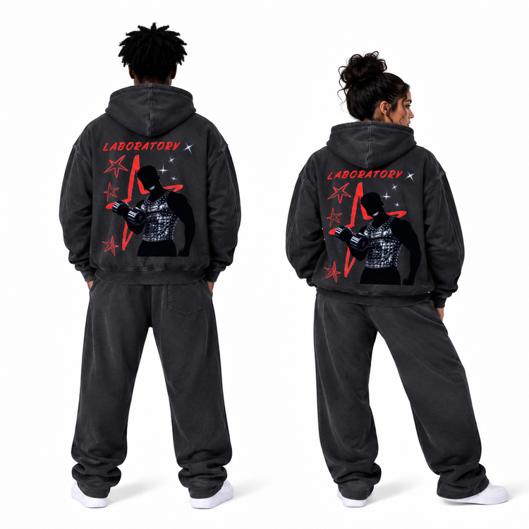 Two models shown from the back wearing a matching dark gray hooded sweatshirt and jogger sweatpants set. The back of the hoodie features a large graphic print with red 'LABORATORY' text, red stars, and a black-and-white figure illustration.